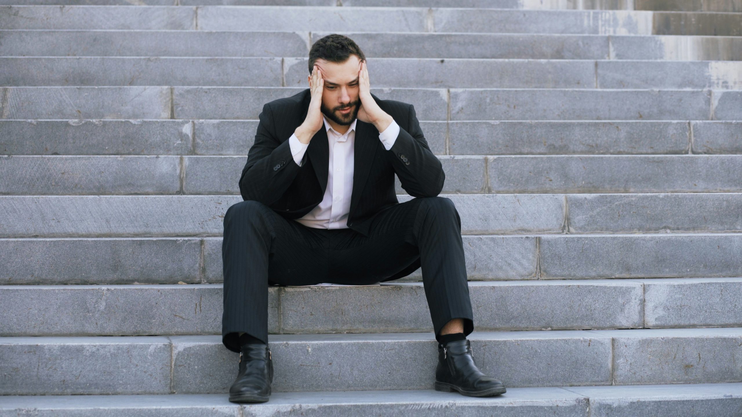 stressed man in a suit, sitting on the stairs